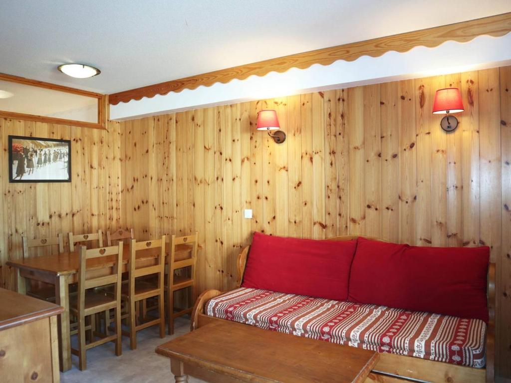 Cette chambre dispose de murs en bois, d'un canapé rouge et d'une table. dans l'établissement Charmant T2, Accès Piscine, Sauna, Ski-In/Out, Balcon Ouest, 6 Pers - Les Orres 1800 - FR-1-322-343, aux Orres