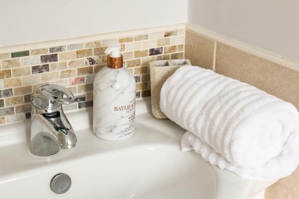 a bathroom sink with a towel and a bottle of soap at Perrys in Poole