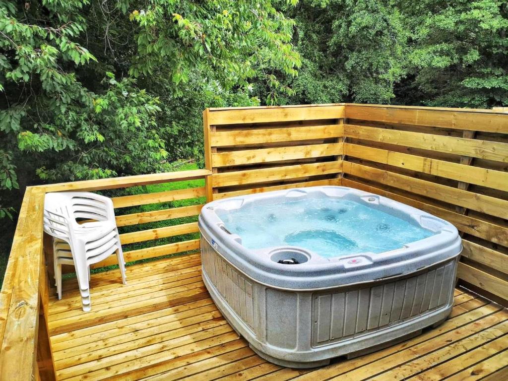 a hot tub sitting on a wooden deck with a chair at Kingfisher Lodge-HuntersMoon -Warminster-Longleat-Bath in Warminster