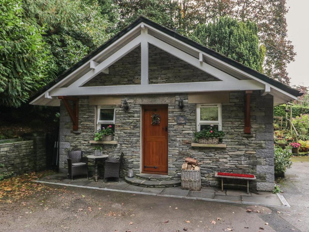 Cette petite maison en pierre dispose d'une porte et d'une table. dans l'établissement The Homestead Lodge, à Windermere