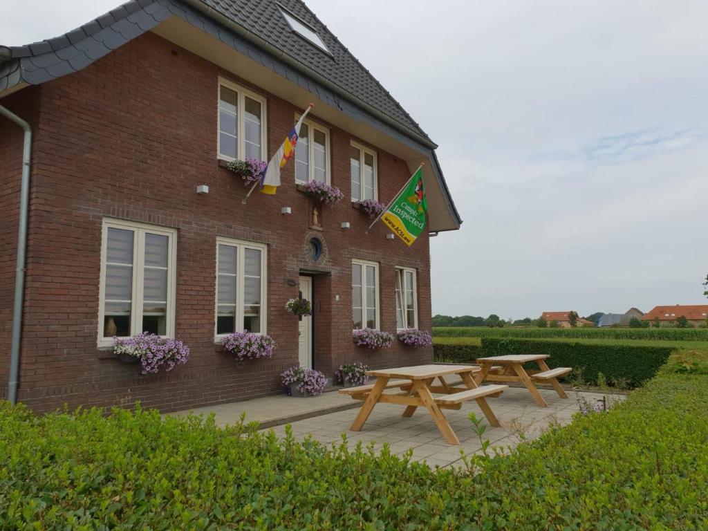 HeijenrathにあるB&B Flamandのピクニックテーブルと旗が掲げられた建物