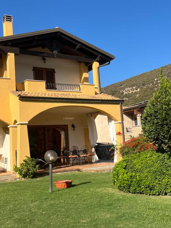 een geel huis met een tuin en een patio bij La Casa sulla collina "Baccu e Idda" in Chia