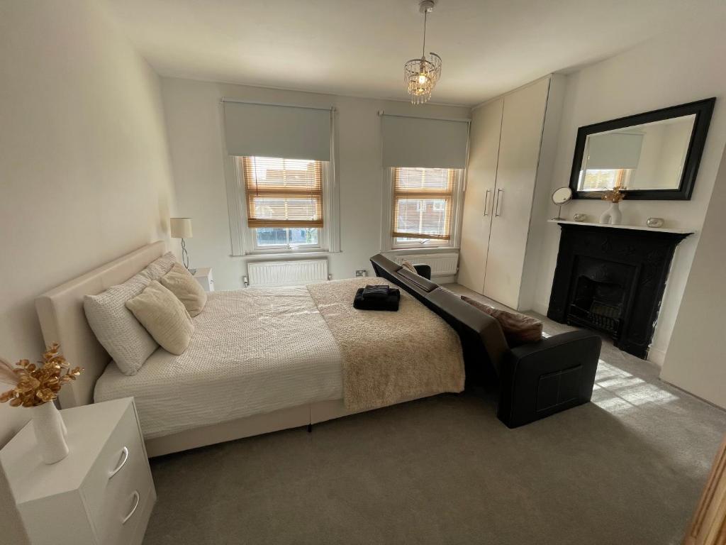 a white bedroom with a bed and a fireplace at A lovely Three bedroom house in Windsor in Windsor