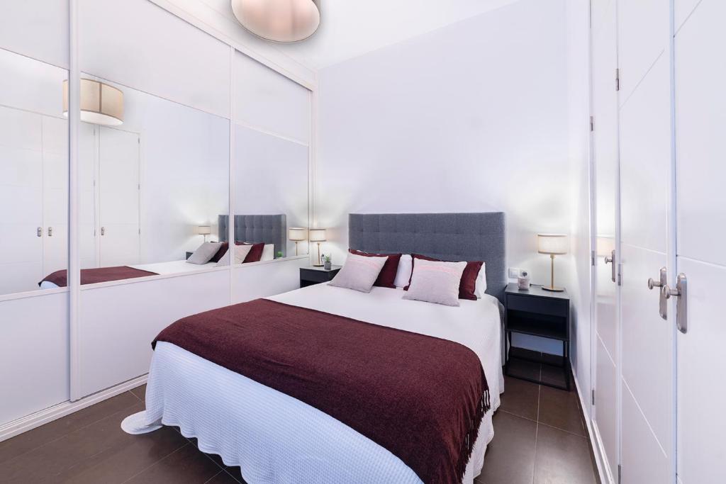 een witte slaapkamer met een groot bed en een spiegel bij AlohaMundi Campana II in Sevilla
