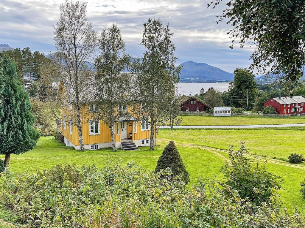 una casa amarilla en un campo verde con montañas al fondo en 6 person holiday home in AVERØY-By Traum, en Stein