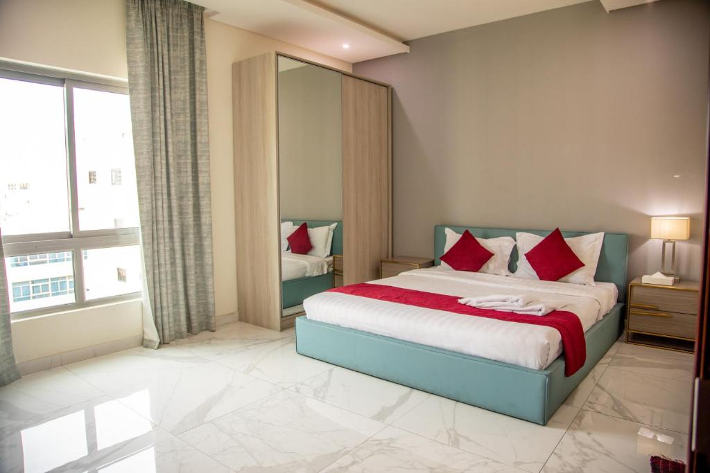 una camera da letto con un grande letto con cuscini rossi di The Apple Residence a Juffair