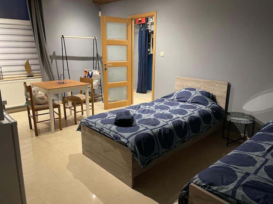 a bedroom with a bed and a table and a chair at Studio proche de l’aéroport/gare/centre ville in Charleroi
