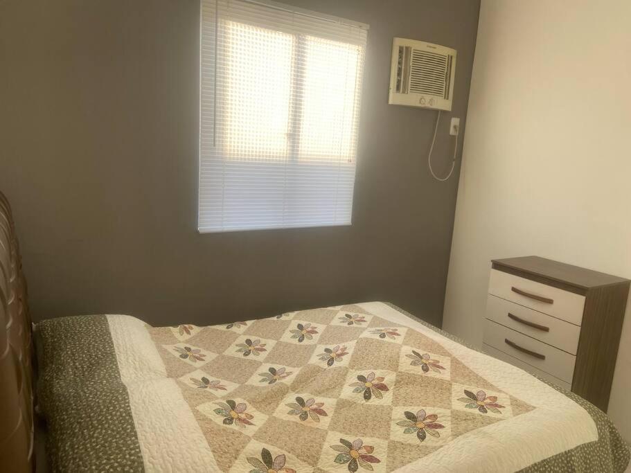 um quarto com uma cama com uma colcha e uma janela em Apartamento mobiliado em Maricá próximo ao centro em Maricá