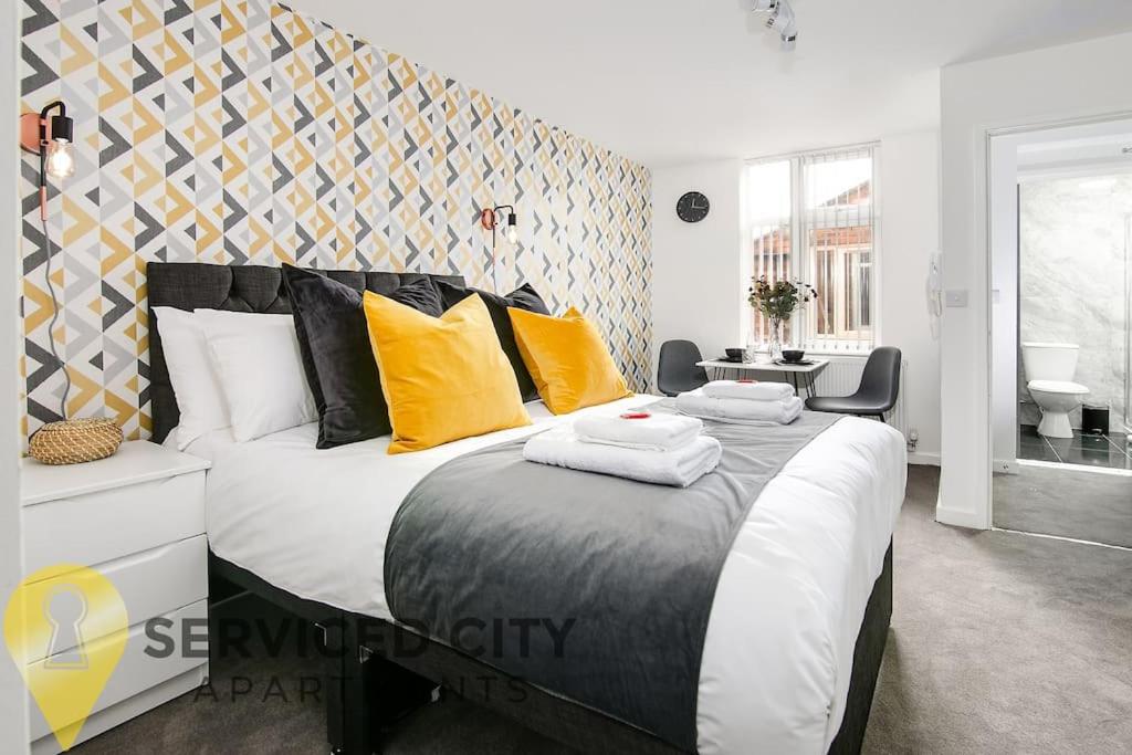a bedroom with a large bed with yellow pillows at SCA - Enjoyable Studio - VS1 in Wolverhampton