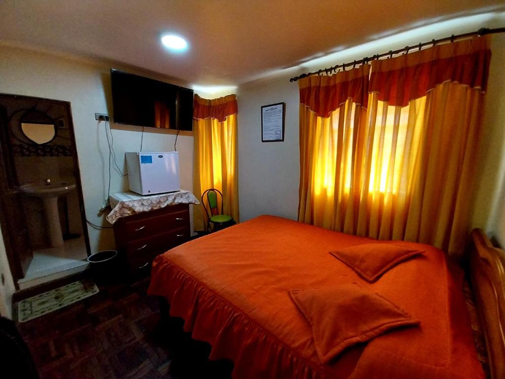 a bedroom with a bed with orange sheets and curtains at Residencial 10 de Noviembre in Potosí