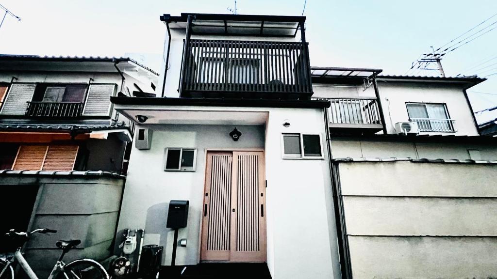 een wit gebouw met een rode deur en balkons erop bij 花田屋HANADAYA in Nishinotōindōri