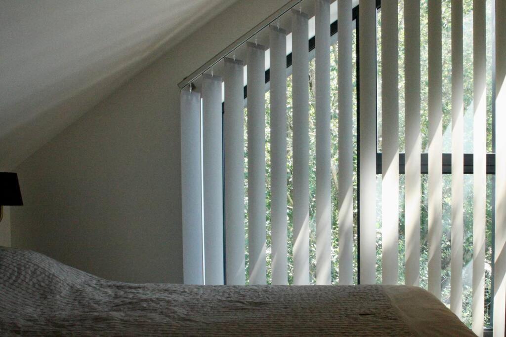 ein Schlafzimmer mit einem Fenster mit vertikalen Jalousien in der Unterkunft Appartement lumineux in Dole