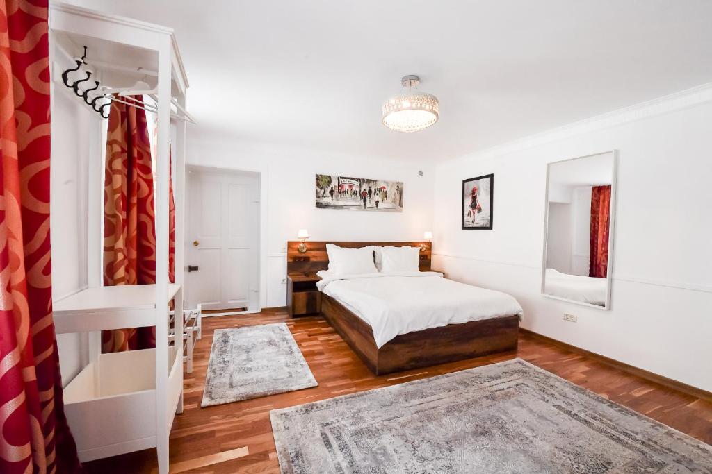 a white bedroom with a bed and a desk at FiveRooms in Braşov