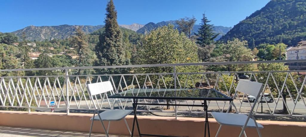 een tafel en 2 stoelen op een balkon met uitzicht op de bergen bij Refuge Arago in Vernet-les-Bains