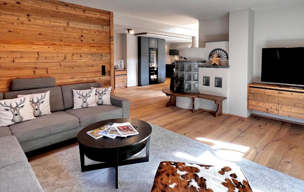 a living room with a couch and a tv at BOUTIQUE KAISERLODGE mit privater SAUNA & WHIRLPOOL by Belle Stay in Kitzbühel