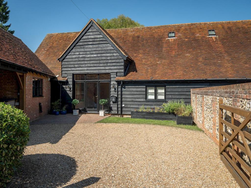 a house with a wooden fence and a driveway at Pass the Keys Bradenham Barn in The Chiltern Hills in Bradenham