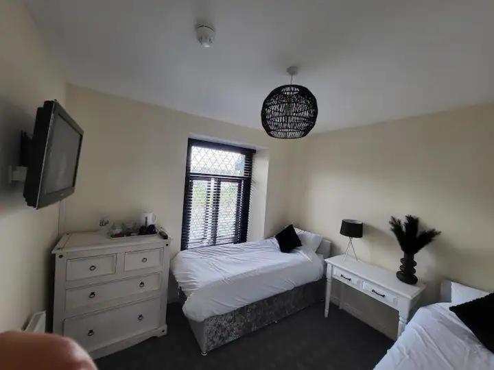 a bedroom with a bed and a dresser and a television at The Dublin Packet - Twin Room in Holyhead