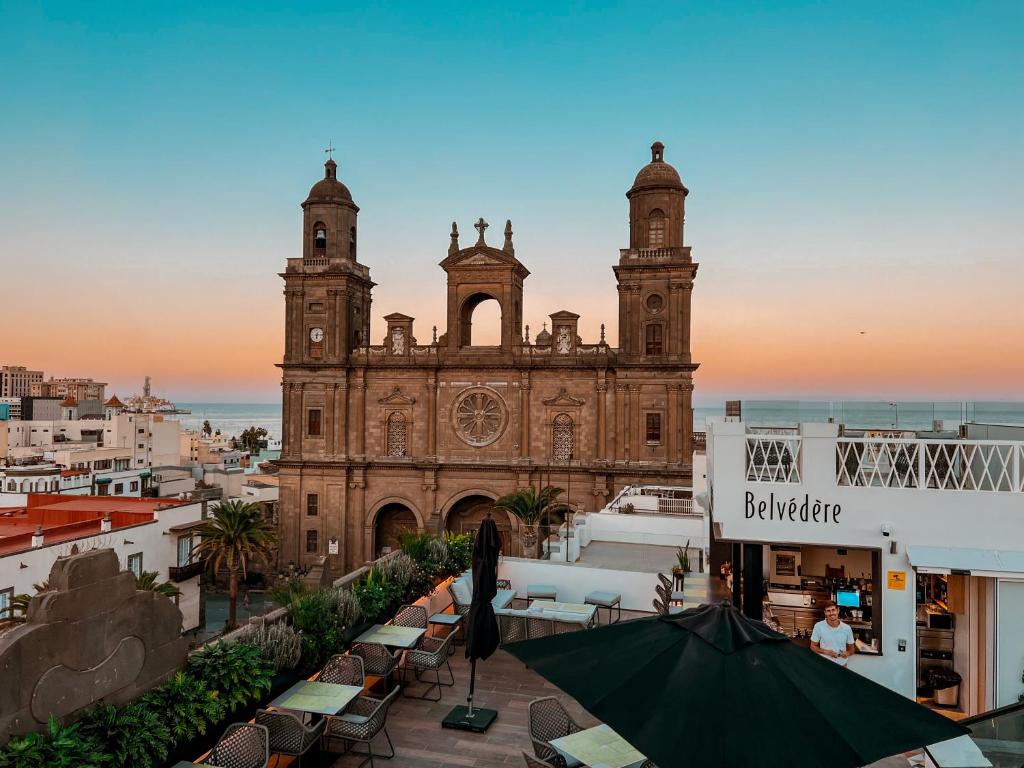 um edifício antigo com uma torre de relógio em frente em Boutique Hotel Cordial Plaza Mayor de Santa Ana em Las Palmas de Gran Canaria