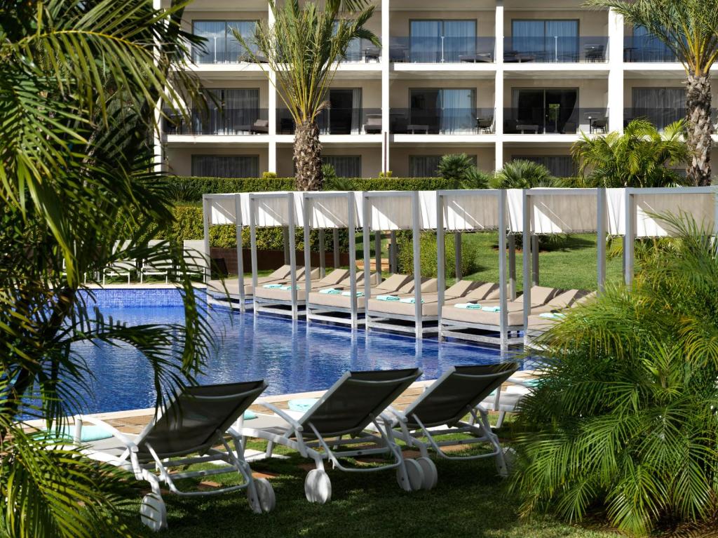 a group of lounge chairs next to a swimming pool at Zafiro Palace Palmanova in Palmanova