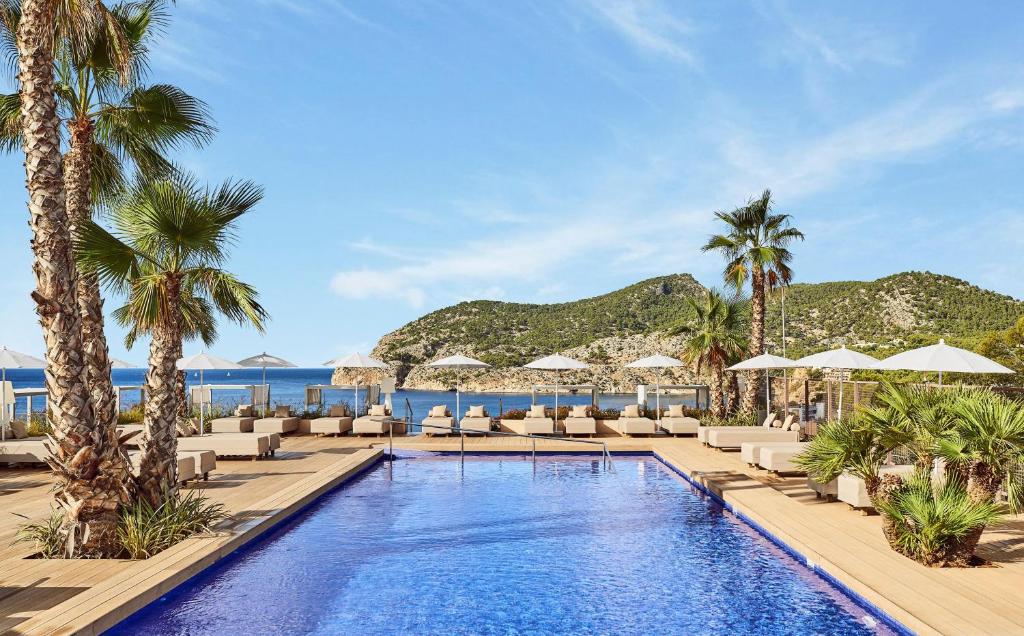 uma piscina com espreguiçadeiras e guarda-sóis num resort em Zafiro Palace Andratx em Camp de Mar