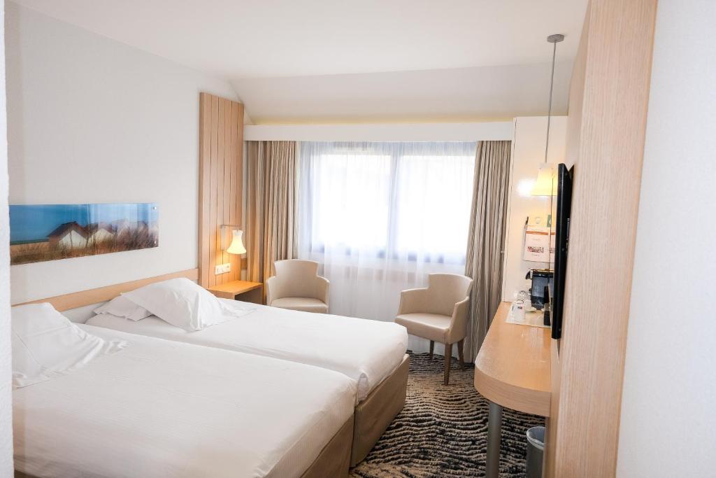 a hotel room with a bed and a desk at Thalazur Ouistreham - Hôtel & Spa in Ouistreham