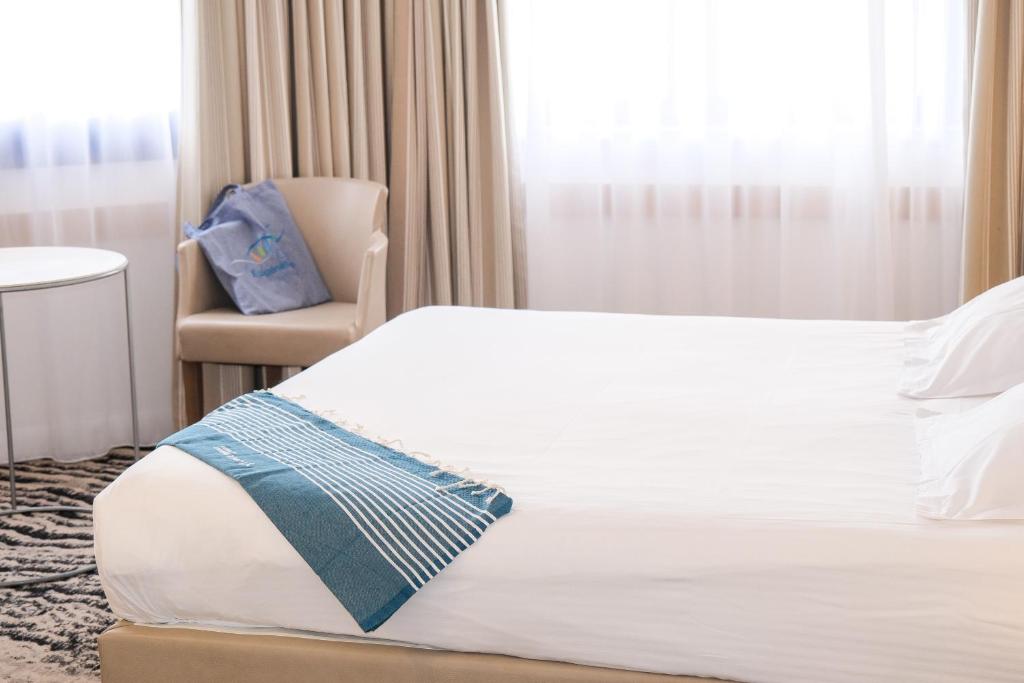 a hotel room with a bed and a chair at Thalazur Ouistreham - Hôtel & Spa in Ouistreham