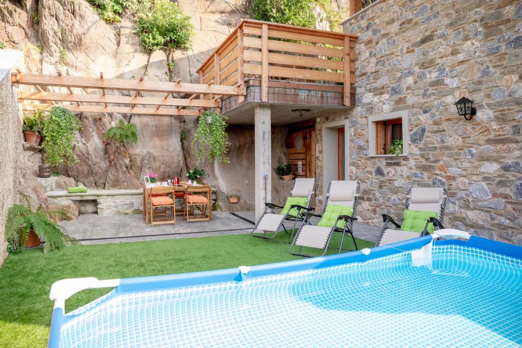 a pool in a yard with chairs and a table at Green Chalet Scalotta - Private Garden with Pool in Dervio