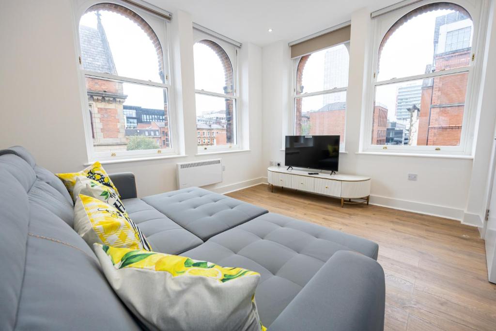 a living room with a gray couch and windows at Amazing 1BD Apartment China Town Manchester in Manchester