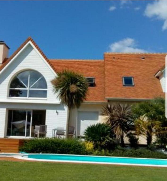 une maison avec un palmier devant dans l'établissement chambre Elisa Entre Caen et la mer avec piscine, à Mathieu