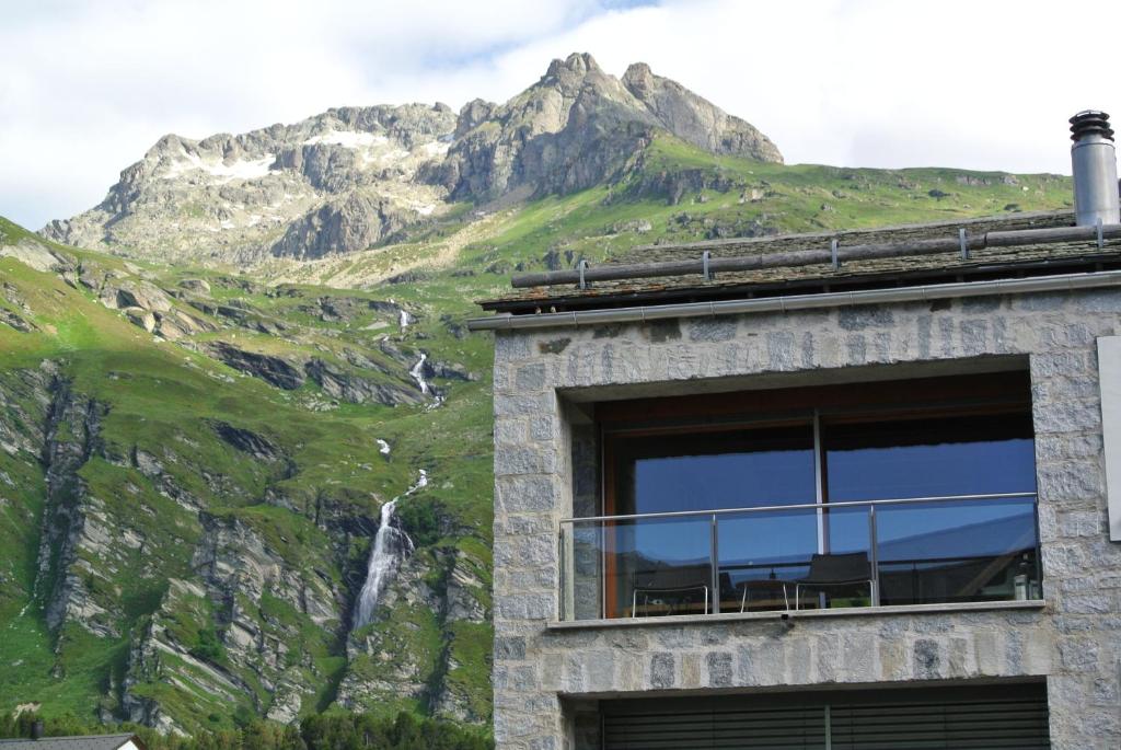 a building with a mountain in the background at Chesa La Montanella - Ferienwohnung, Maloja in Maloja