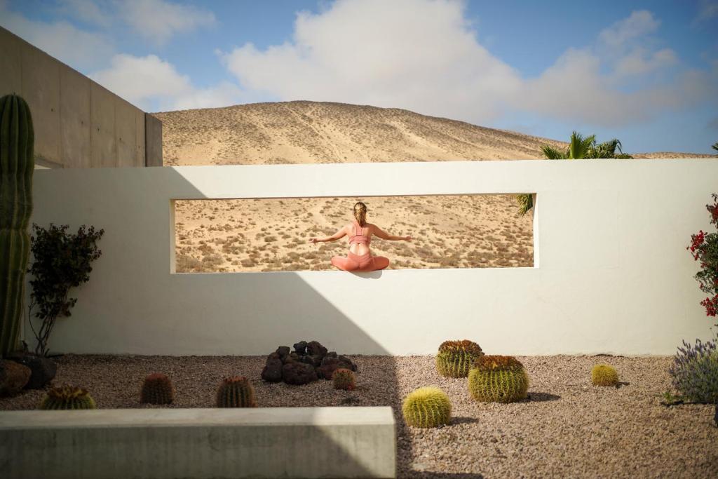 a woman sitting on a wall with a picture of a beach at INNSiDE by Meliá Fuerteventura – Adults Only in Costa Calma