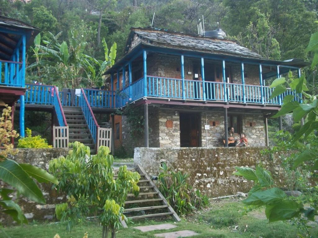 una vecchia casa con balcone blu e scale di Shivanandi River Lodge a Rudraprayāg