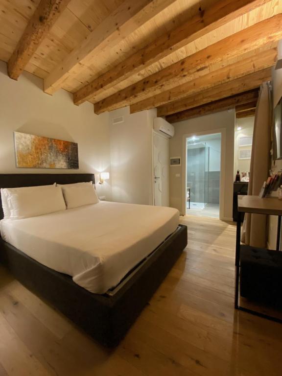 Malvezzi24 Boutique Rooms في ديسينسانو ديل غاردا: غرفة نوم بسرير كبير وسقوف خشبية