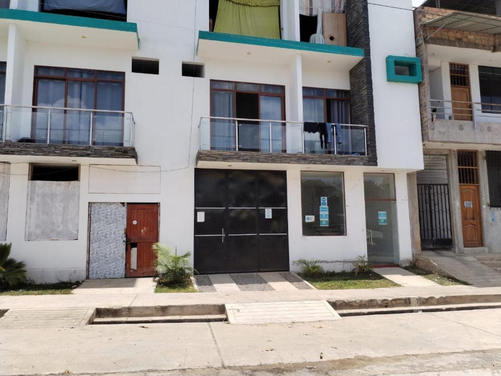 biały budynek z dwoma drzwiami i balkonem w obiekcie Hospedaje los robles w mieście Tarapoto