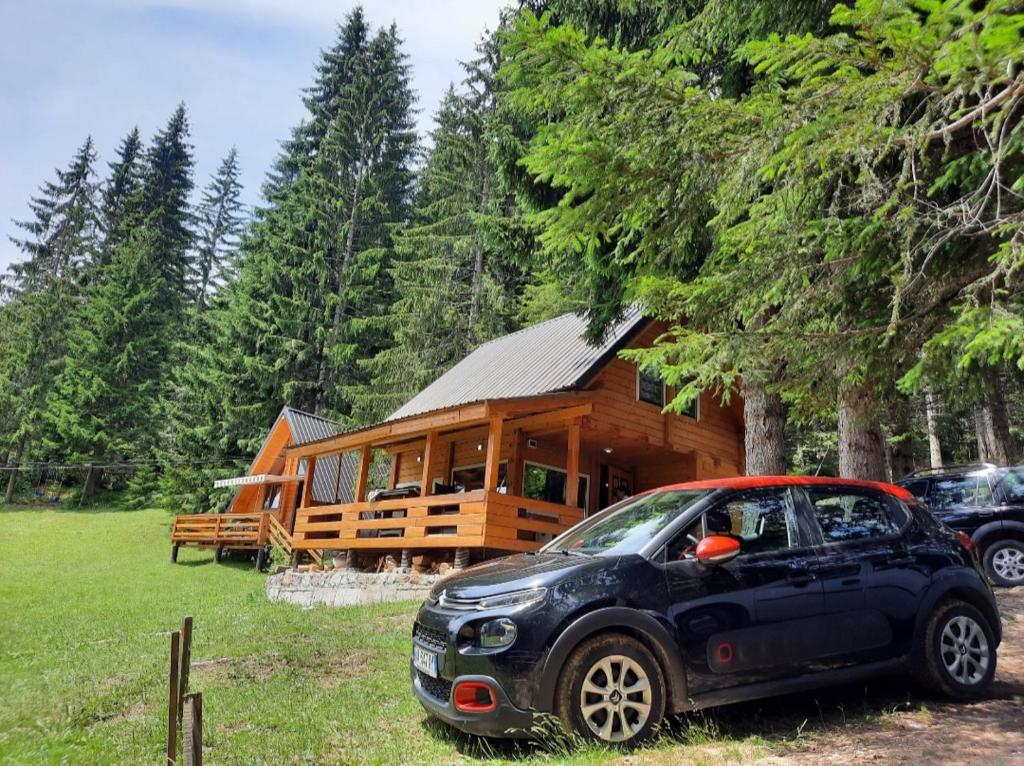 a small car parked in front of a log cabin at Peaks of the Balkans Trail 192 km -- Hostel Panorama -- in Peje