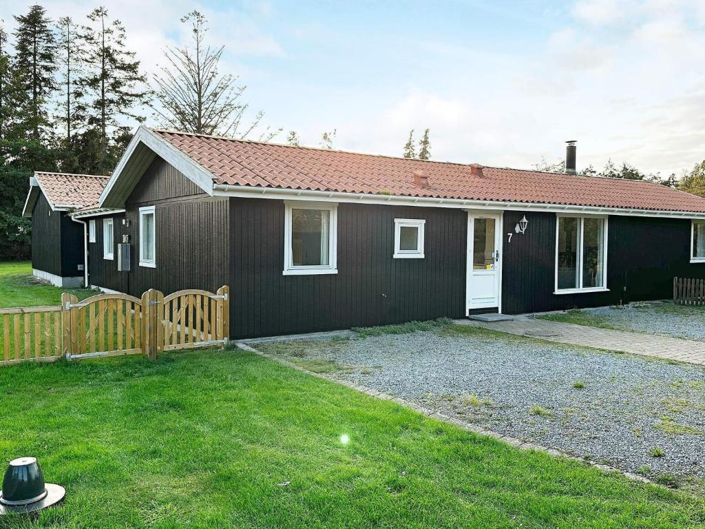 een klein zwart huis met een houten hek bij Holiday home Væggerløse CCXVI in Bøtø By