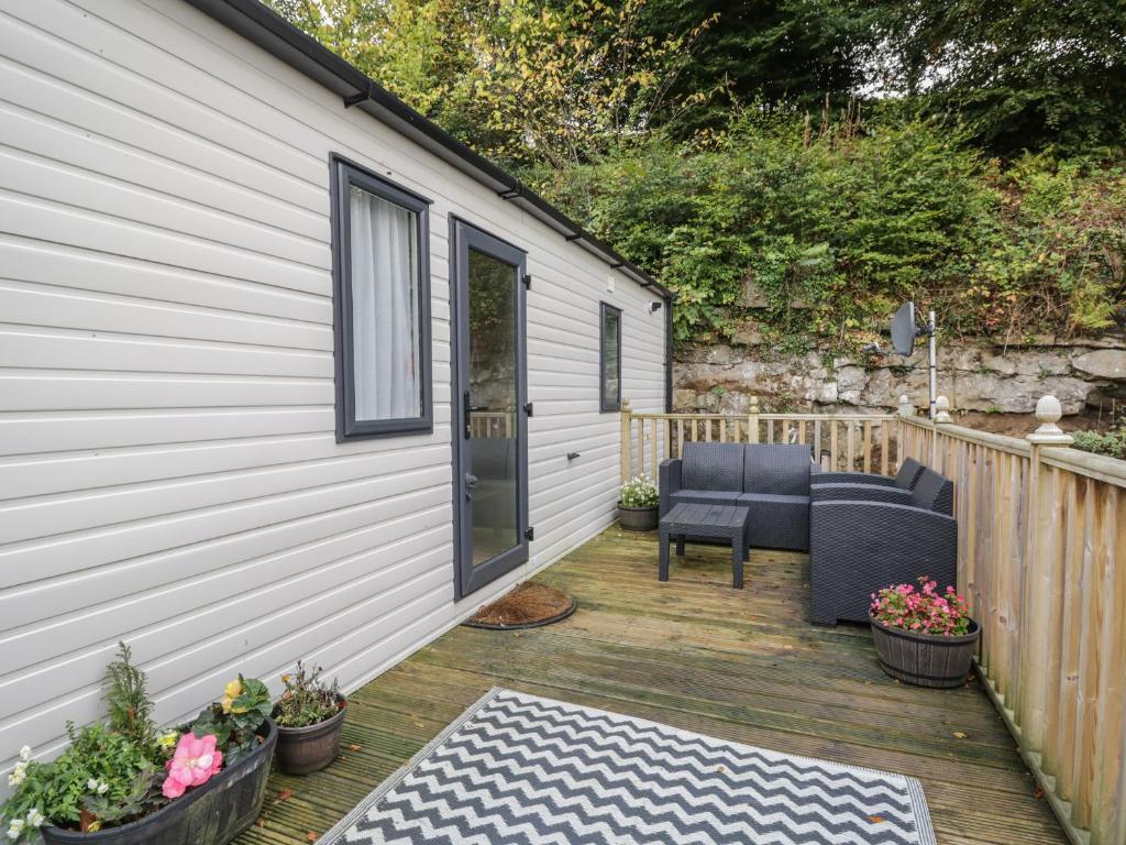 a wooden deck with two chairs and a door at Burlees Nest in Cockermouth