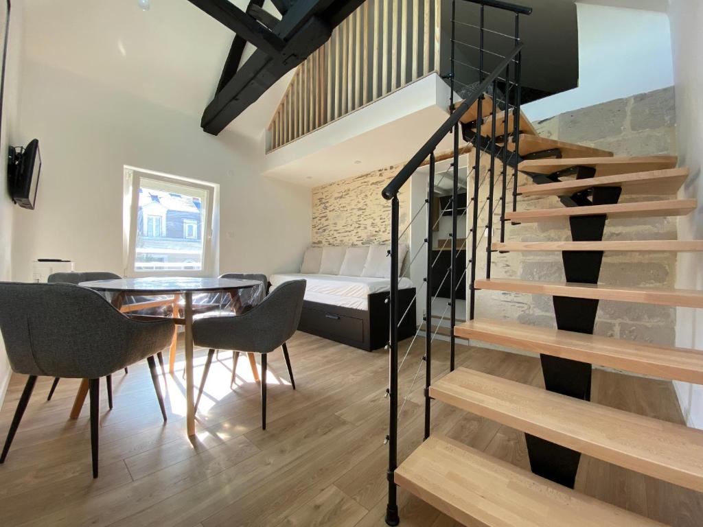 une pièce avec une table, un escalier et un lit dans l'établissement La Douce Angevine - Le Perroquet, à Angers