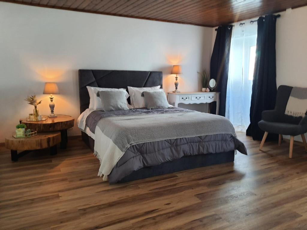 a bedroom with a large bed and a wooden floor at Stone House in Lagoa