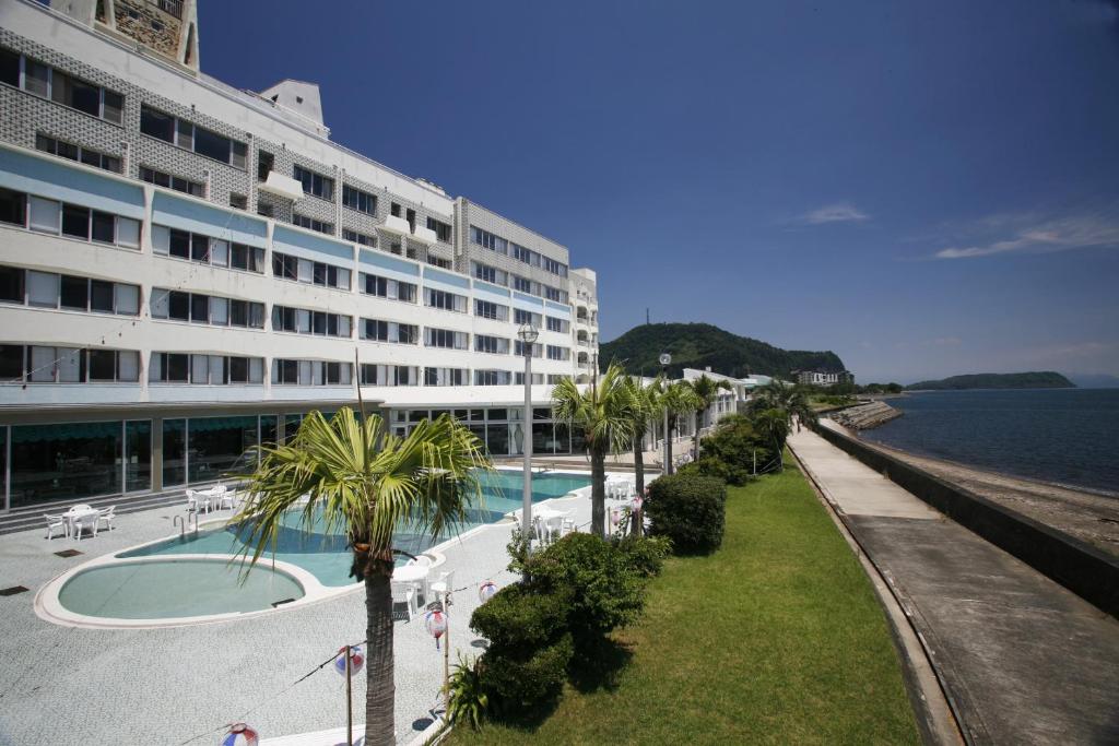 a large building with a swimming pool next to the ocean at Ibusuki Seaside Hotel in Ibusuki