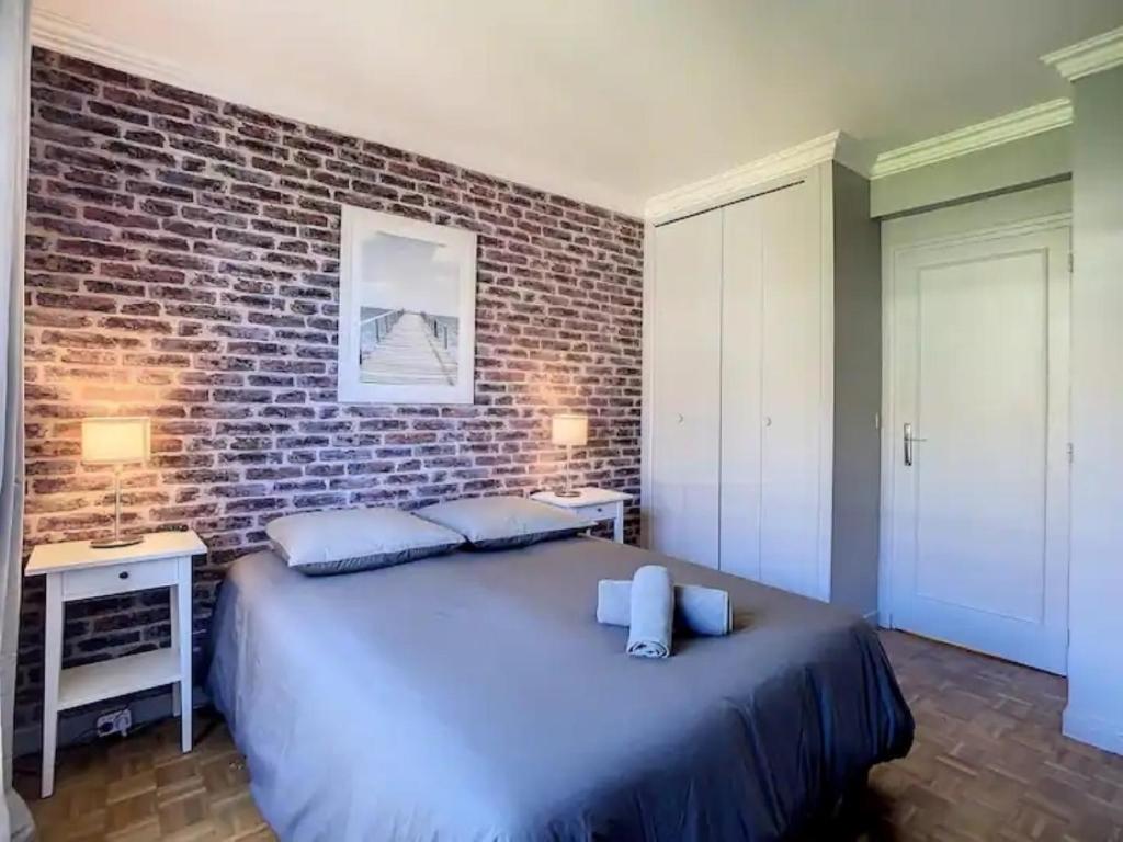Schlafzimmer mit Ziegelwand und großem Bett in der Unterkunft Appartement chic proche de Paris, parking inclus in Saint-Maur-des-Fossés