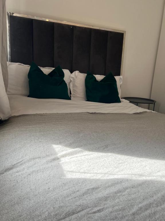 a bed with two green pillows on top of it at Borehamwood stay in Borehamwood