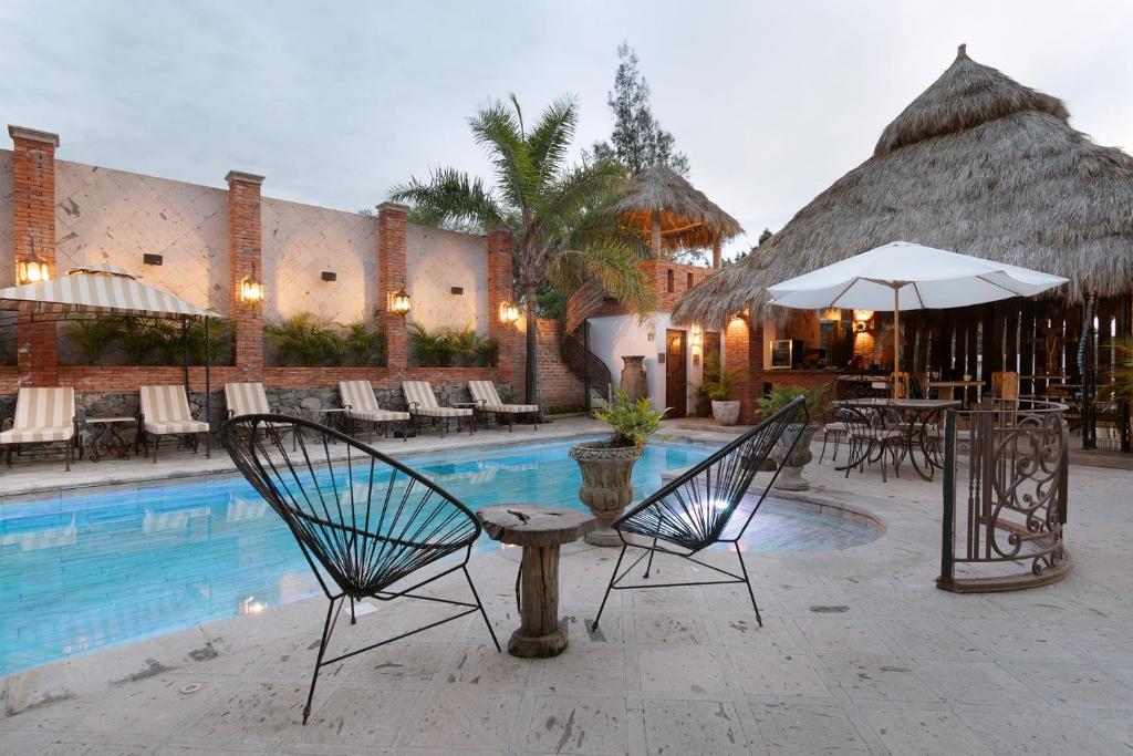 a resort with a swimming pool with chairs and an umbrella at Casa Miura Hotel Boutique in Ajijic