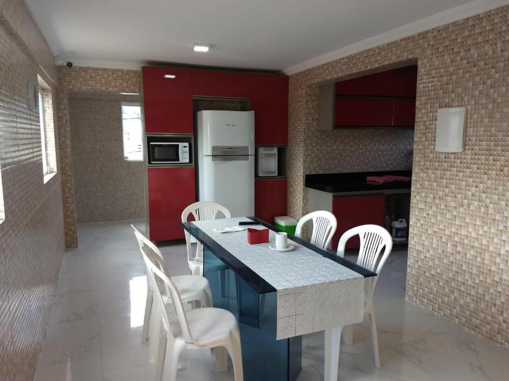 uma cozinha com uma mesa com cadeiras brancas e um frigorífico em CASA COM PISCINA À BEIRA MAR. em Recife