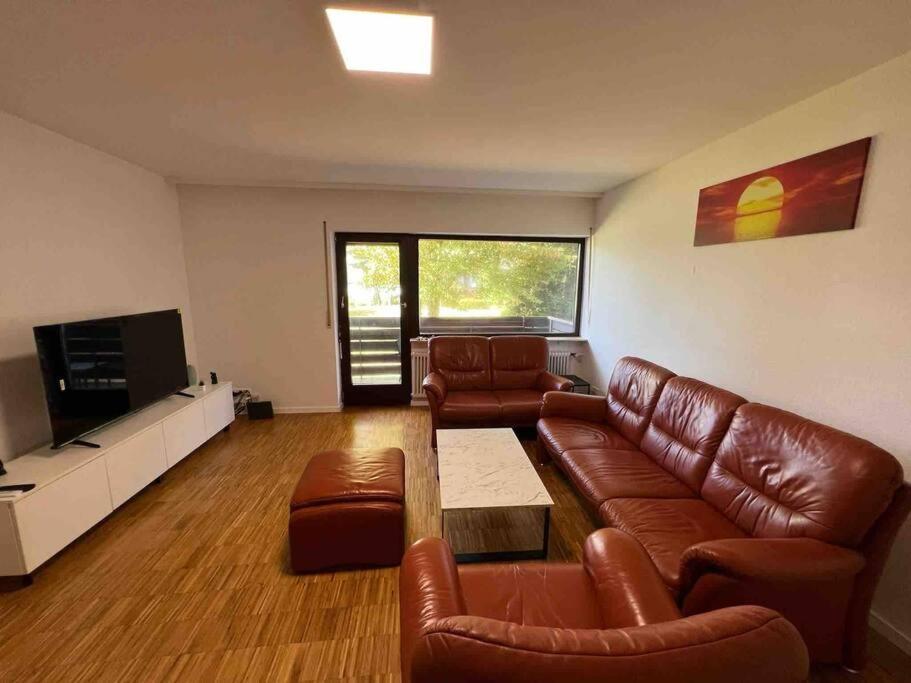 a living room with brown leather furniture and a flat screen tv at Sunset Dreams Apartment in Bühl
