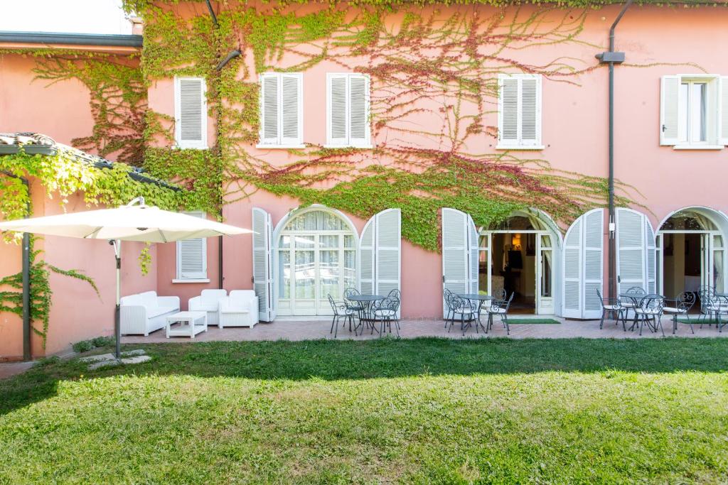 ein rosafarbenes Gebäude mit Stühlen und einem Regenschirm in der Unterkunft Hotel Sant'Andrea in Ravenna