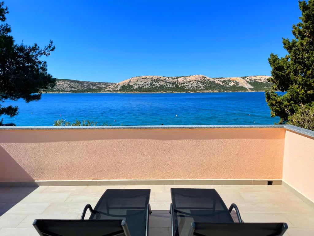 a group of chairs sitting on a patio overlooking the water at Villa Olivija-direkt am Strand! in Stara Novalja