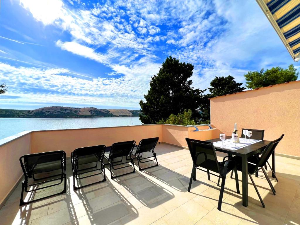 a table and chairs on a patio with a view of the water at Villa Olivija-direkt am Strand! in Stara Novalja