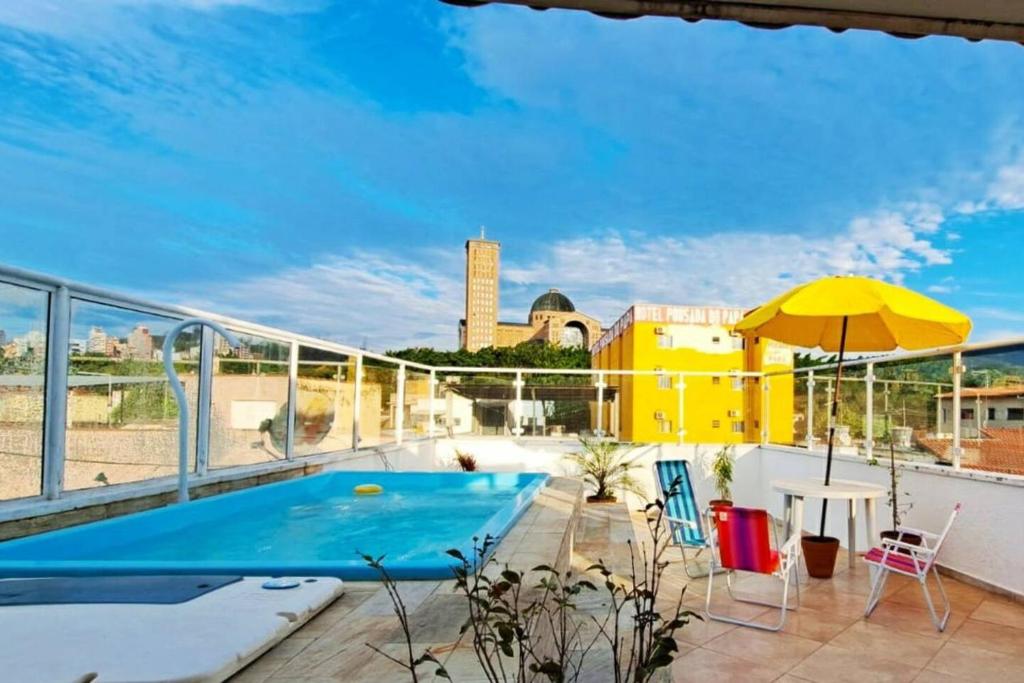 a balcony with a swimming pool and a table and an umbrella at Casa de Maria in Aparecida