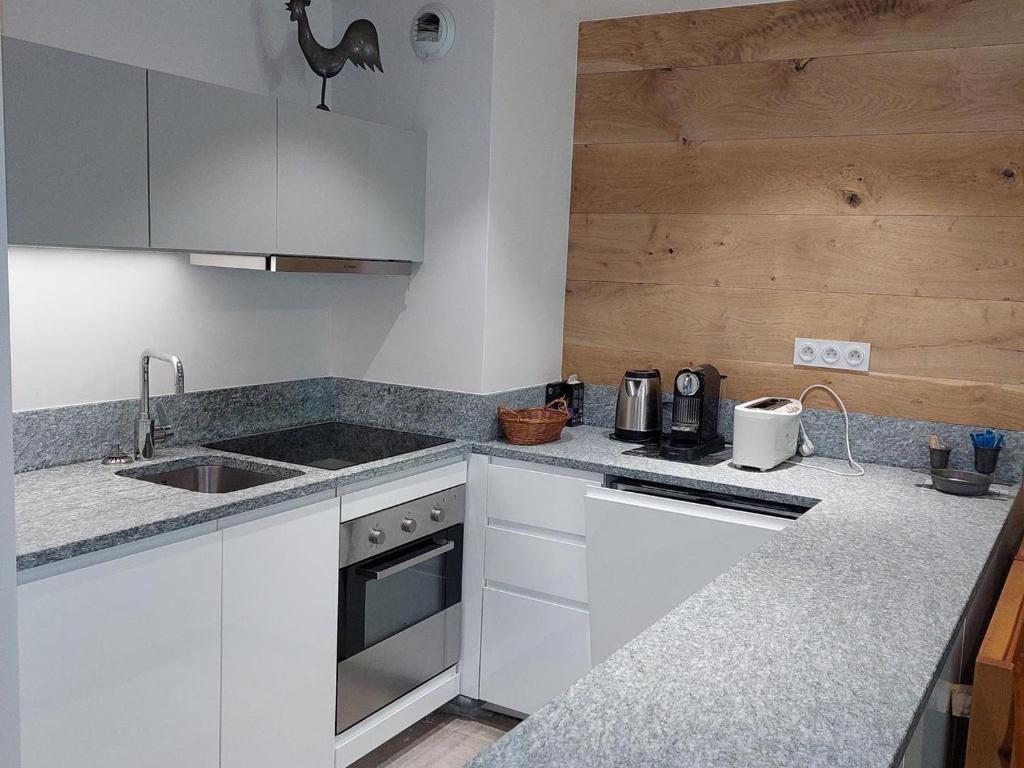 une cuisine avec des armoires blanches et un comptoir dans l'établissement Duplex rénové 3 pièces avec jardin, parking et animaux admis à Chamonix - FR-1-517-25, à Chamonix-Mont-Blanc